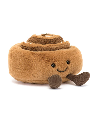 The Jellycat Amuseables Cinnamon Bun plush toy is shaped like a cinnamon bun, featuring a smiling face with embroidered eyes and mouth, small brown feet for added charm, and a light brown exterior with darker swirls.