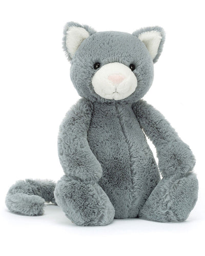 Introducing the Jellycat Bashful Kitten, a cute plush toy with soft grey fur, white inner ears, a white snout, and a pale pink nose. This charming stuffed animal sits upright with its tail curled beside it against a plain white background.
