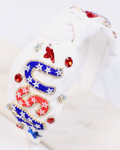 The USA Embellished Headband - White features red, blue, and silver sequins and beads forming "USA" and star shapes—a festive accessory perfect for celebrating in patriotic style.