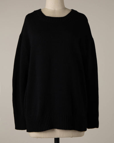 The Lyla Cable Knit Ribbed Soft Pullover Sweater in black is showcased on a dress form against a simple beige backdrop. This sweater highlights a crew neckline, long sleeves, and a relaxed fit.