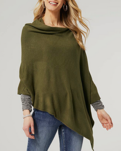 A person is wearing the Kayley Lightweight Poncho in olive, featuring an asymmetrical hem, over a gray long-sleeve shirt and blue jeans. Their blonde hair is styled in loose waves, and they are smiling. Hoop earrings enhance the chic look of this perfect layering accessory.
