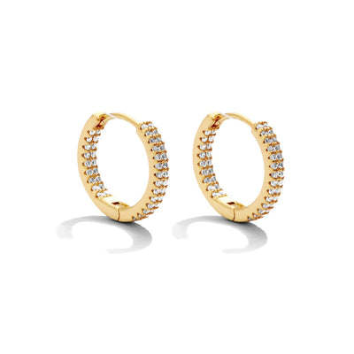 The Small Glitzy Huggies - Gold, adorned with pave cubic zirconia, offer a dazzling and luxurious look. The sparkling gemstones are elegantly arranged, casting subtle shadows against the white background.
