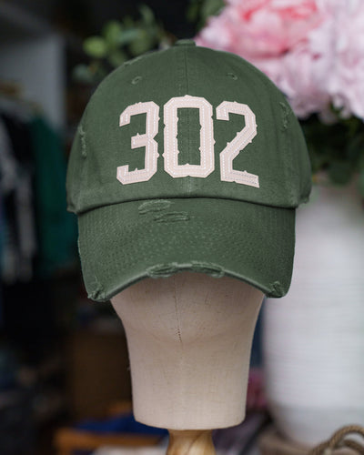 A distressed vintage-inspired baseball hat in Army Green with the number '302' embroidered in tan on the front, displayed on a mannequin head.