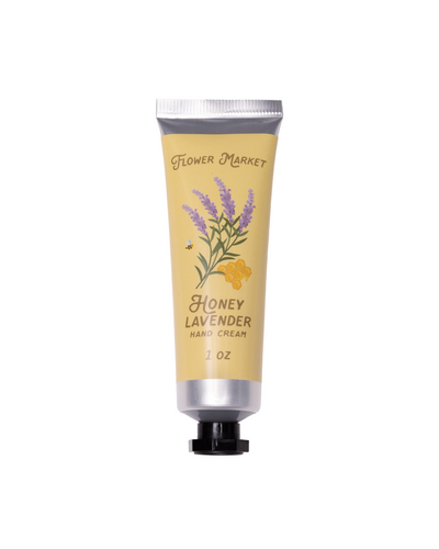 The Flower Market Honey Lavender Hand Cream - 1 oz comes in a yellow, black-capped tube adorned with lavender flowers, honeycomb, a bee, and Shea Butter highlights, shown on a white background.