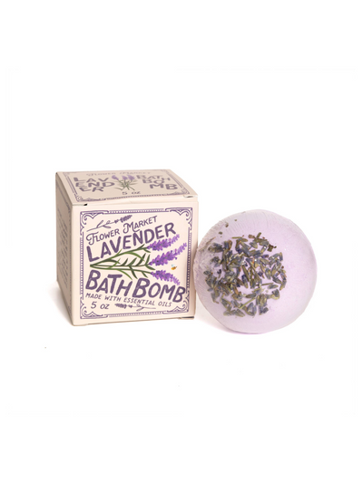 Flower Market Lavender Bath Bomb showcasing a purple bath bomb topped with dried lavender buds, paired with its charming vintage-inspired packaging featuring lavender illustrations and essential oil details.