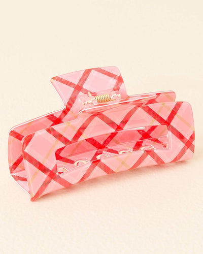 Close-up view of a rectangular acrylic hair claw in a pink plaid pattern with red crisscross lines, showcasing its sturdy clasp and open design.