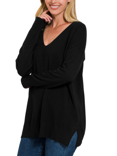 A person wearing an Ashley Front Seam Sweater in black and blue jeans smiles with arms crossed.