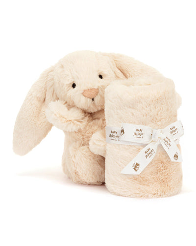 Jellycat Bashful Luxe Bunny Willow Soother: A plush bunny sitting upright, holding a rolled-up soft blanket secured with a white ribbon that has Jellycat branding.