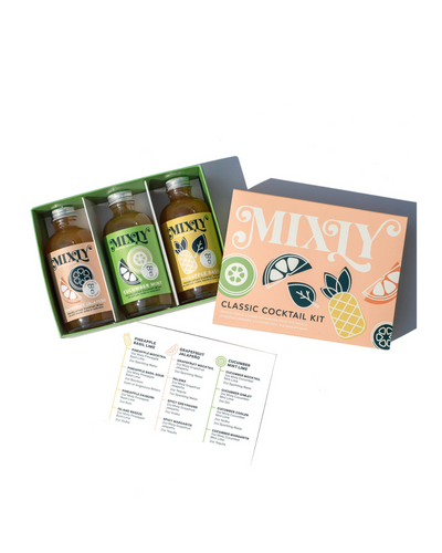 The Mixly Classic Cocktail Kit includes three bottled mixers made with handcrafted ingredients, packaged in a box with a decorative fruit-illustrated lid and a recipe card, all displayed on a white background.