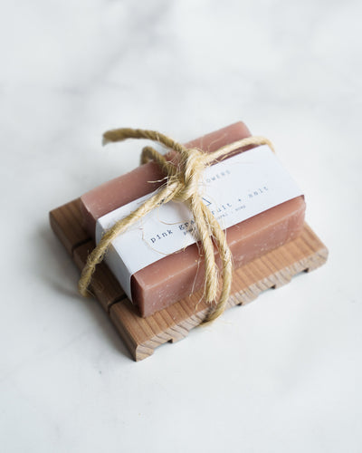 The Soap + Deck Bundle - Pink Grapefruit + Salt features two bars tied with rustic rope on a redwood soap deck. The top bar includes a white label, all set against a smooth white background.