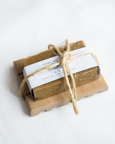 The Soap + Deck Bundle - Sea features two handmade soaps wrapped in white paper and tied with rustic twine, elegantly displayed on a Redwood Soap Deck against a simple white background.