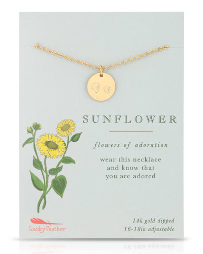 A vibrant gold-dipped necklace with a circular pendant etched with a sunflower design, symbolizing adoration. Displayed on a card with sunflower artwork and the phrase "Flowers of Adoration."
