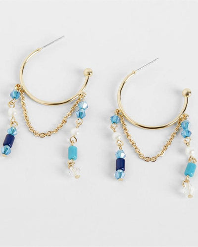 Selena Earrings - Blue: Boho hoop earrings with gold chains, beaded design in vibrant blue and turquoise, and clear crystal accents, shown on a white background.