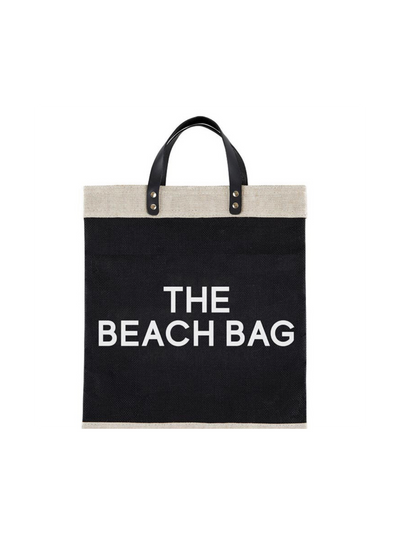 The Black Market Tote - The Beach Bag is a chic accessory with black handles and metal rivets. "THE BEACH BAG" is printed in white on the black section. Made of genuine leather, it features a waterproof lining for practicality.